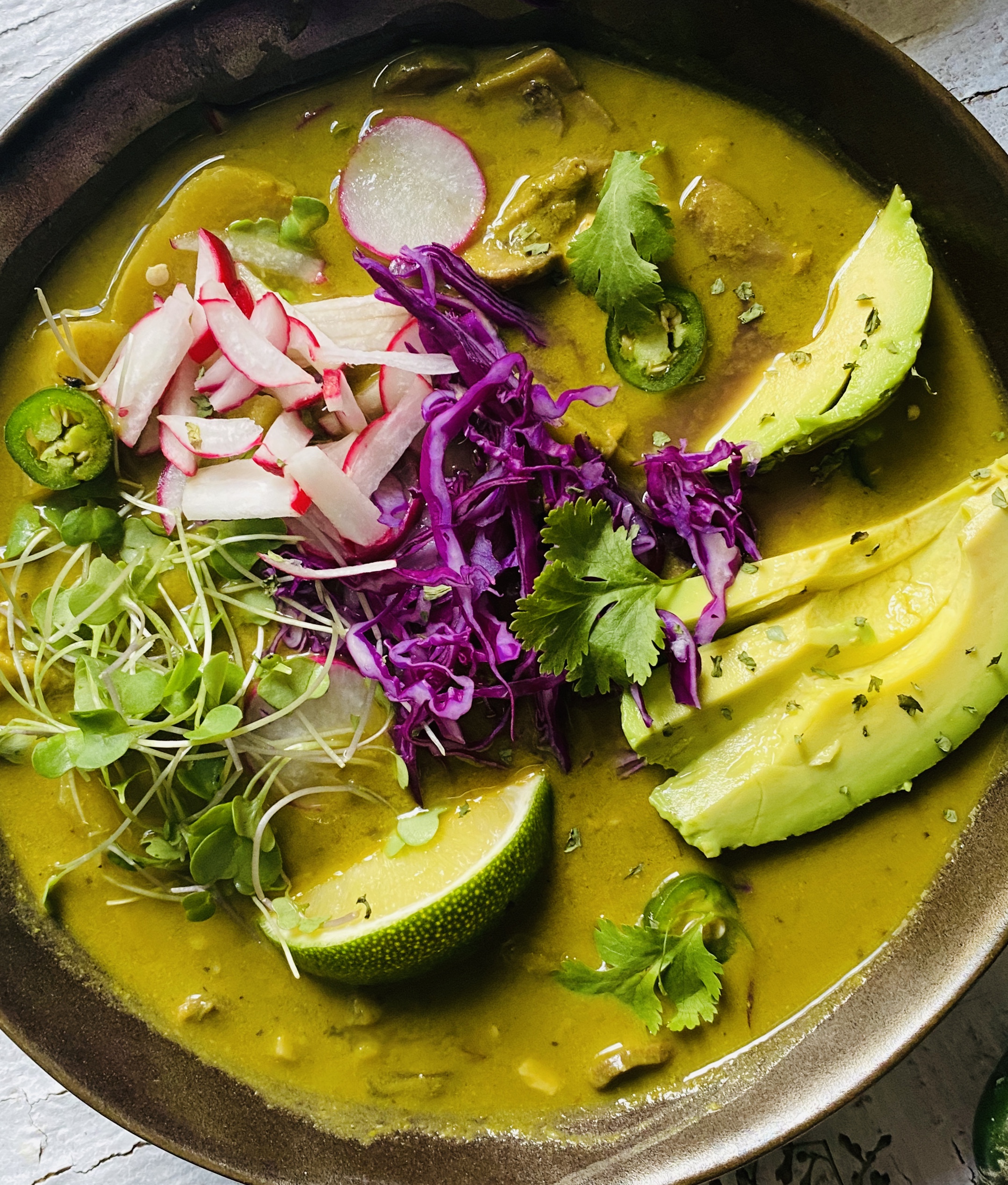 Photo of soup with tomatillos and red cloth in background