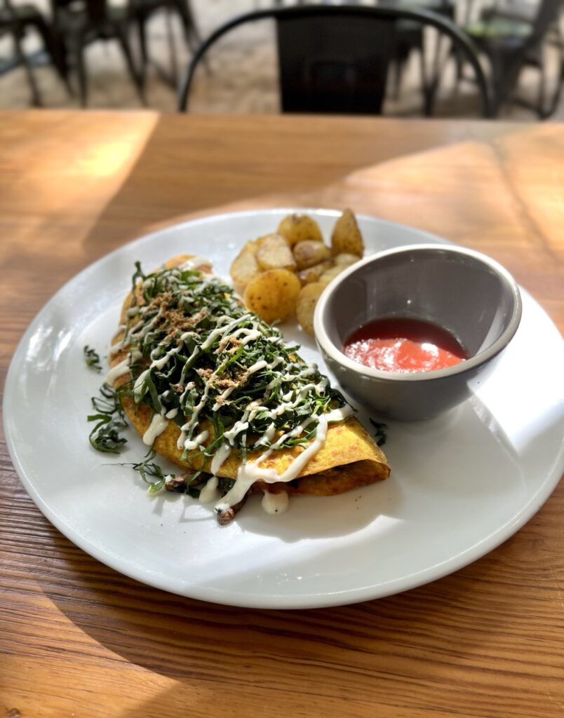 Plate on a table with omelette, ketchup and potatoes