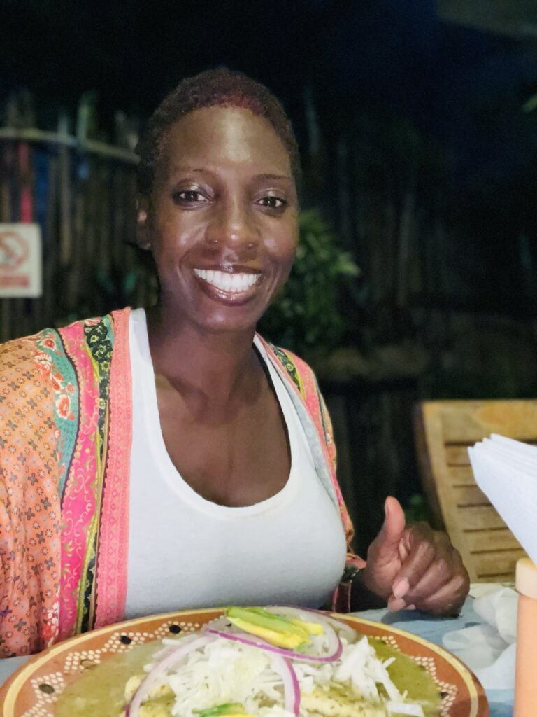 Lady sitting at table with a plate of food at night