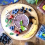 Overhead photo a a mixed berry chia smoothie surrounded by berries and a banana.
