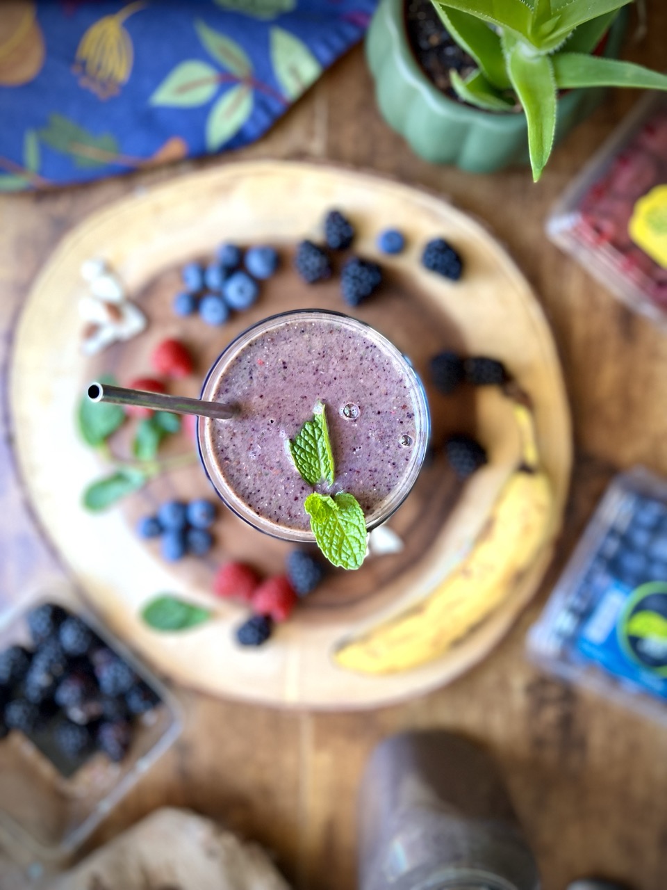 Overhead photo a a mixed berry chia smoothie surrounded by berries and a banana.