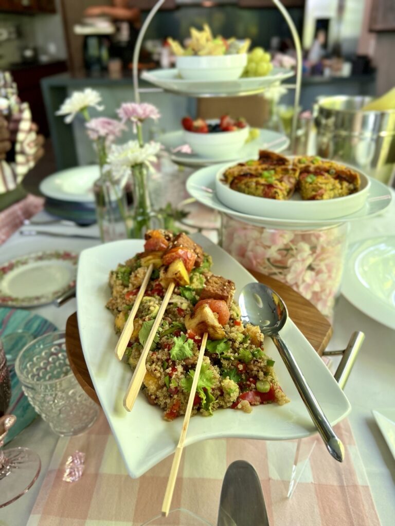 A table filled with several dishes including a plate with tofu skewers,