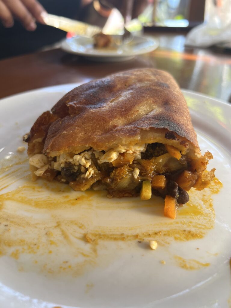 empanada with filling spilling out on plate
