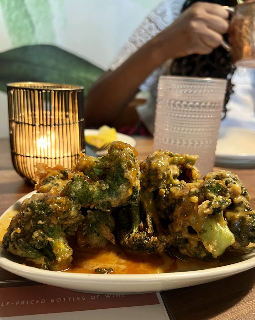 Fried broccoli on a plate with a candle in the background