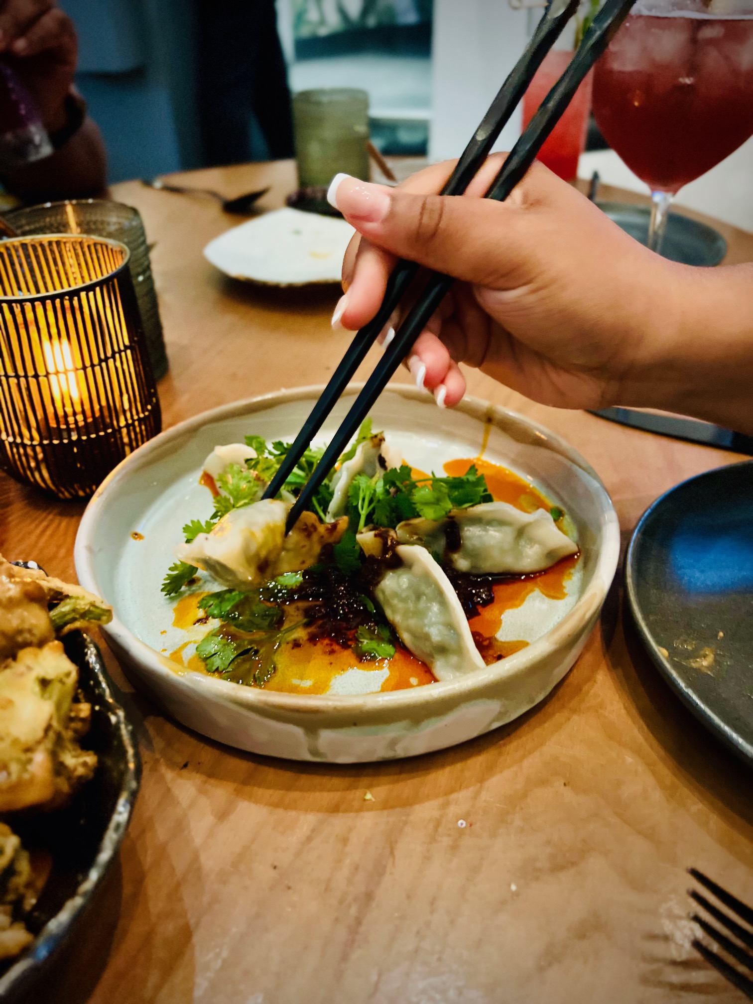 Gyoza dumplings with chili sauce being picked up with chopsticks