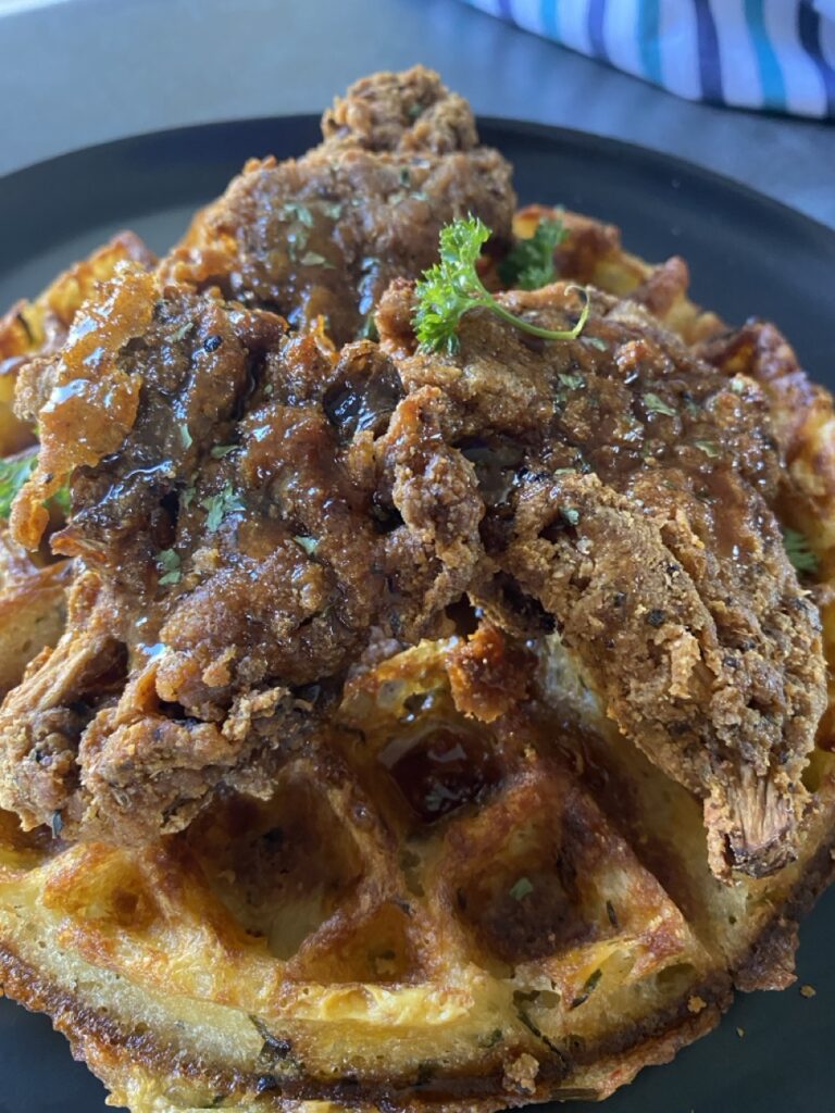 Close up photo of air fried oyster mushrooms and waffle glazed with hot honey maple syrup.