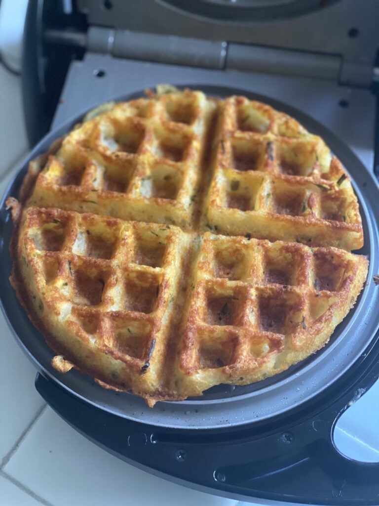 Crispy mashed potato waffle inside waffle iron.