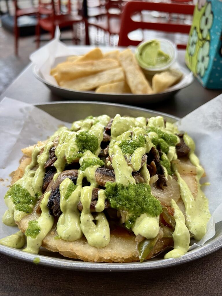 Image of athe Veggie Arepica, a traditional corn cake that’s grilled or fried and served with a variety of toppings including 
•	sautéed mushrooms
•	onions
•	bell peppers
•	hogao (a classic Colombian tomato and onion sauce)
•	cilantro
•	spicy jalapeño relish
