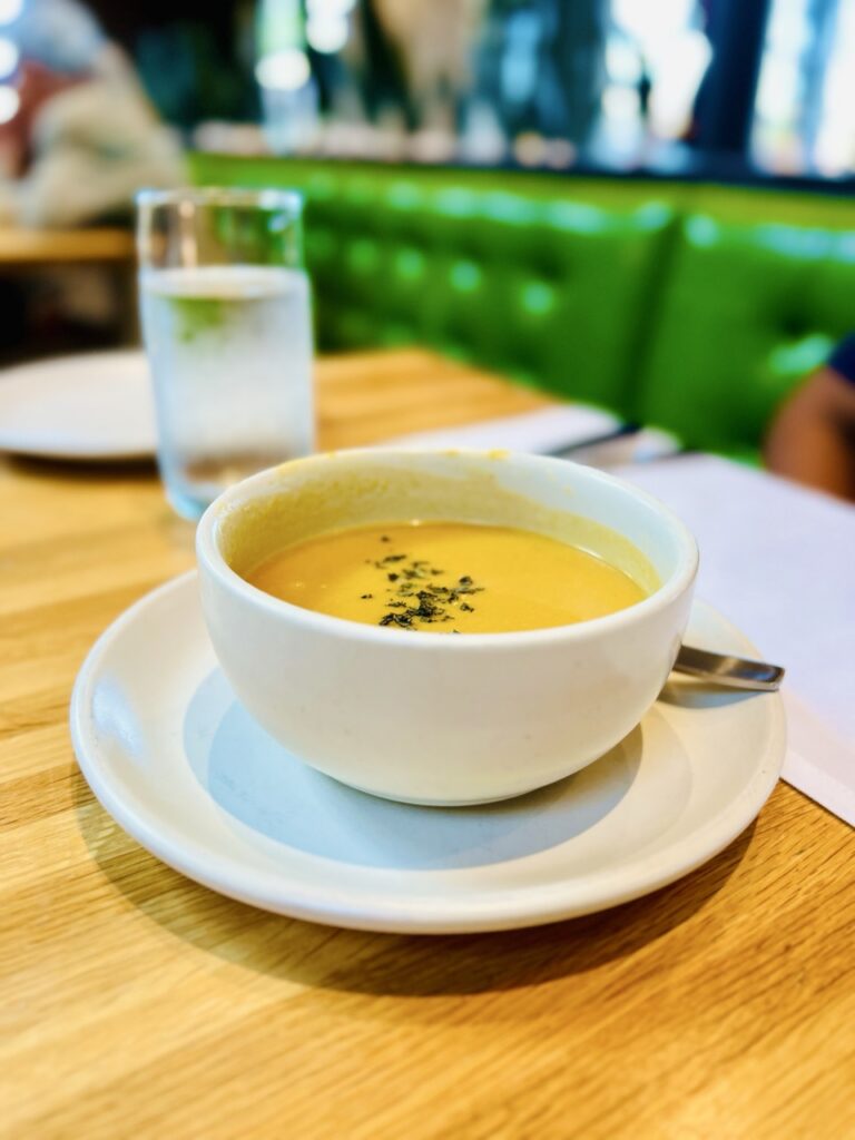 Bowl of butternut squash soup in a saucer sitting on a table.