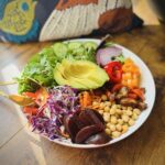 Beautiful picture of Everything said with field greens, arugula, shredded carrots, bell peppers, red onions, avocado, dates, beets, chickpeas, pumpkin seeds, and tomatoes.