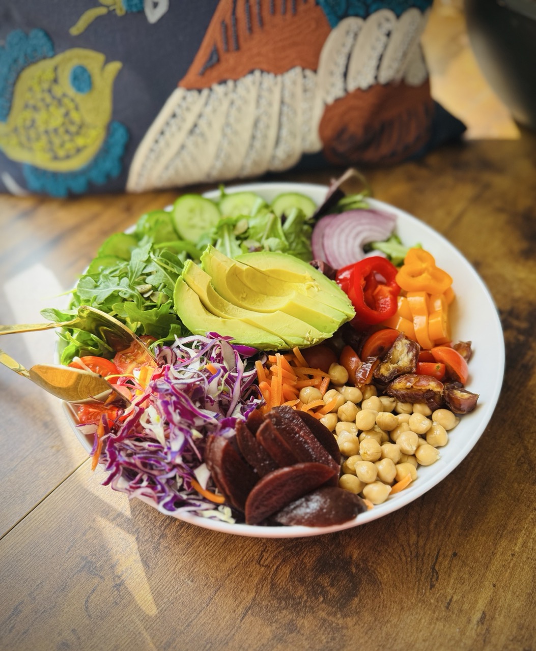Beautiful picture of Everything said with field greens, arugula, shredded carrots, bell peppers, red onions, avocado, dates, beets, chickpeas, pumpkin seeds, and tomatoes.