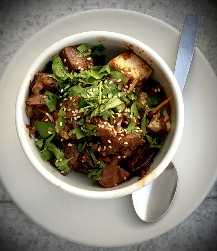 Overhead picture of a bowl filled with jackfruit toped with cilantro on a plate