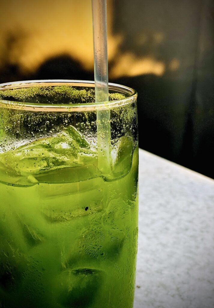 Close up of Kale Ade drink with ice and and straw inside glass