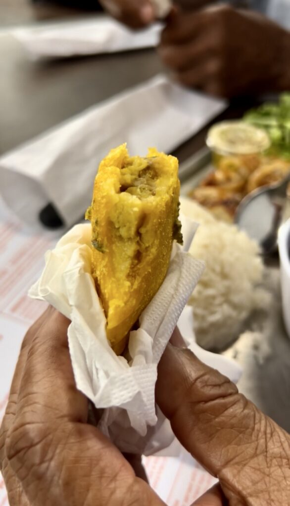 A hand holding a lentil empanada wrapped in a napkin that has been bitten into 