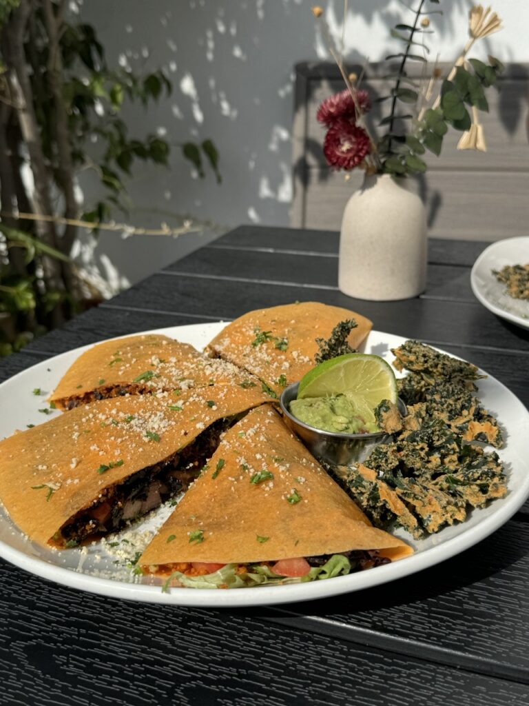 A plate of raw quesadillas served with a side of kale chips