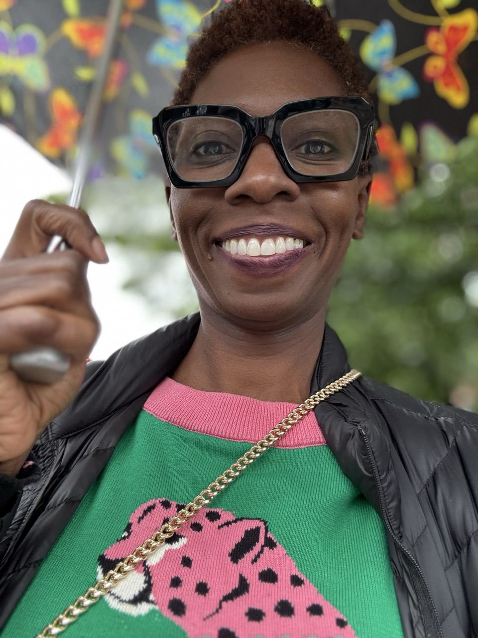Smiling woman wearing glasses holding an umbrella.