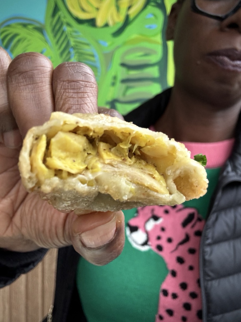 Woman holding a curry chicken wonton showing the inside of the wonton that has been bitten.