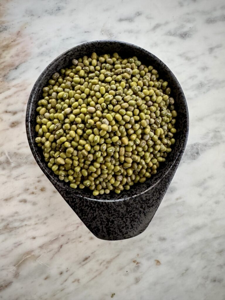 Black bowl on a marble countertop filled with dried mung beans