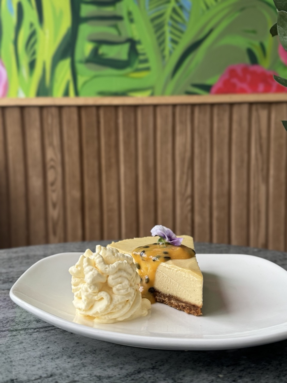 Plate on a table with vegan passionfruit cheesecake and whipped cream on top.
