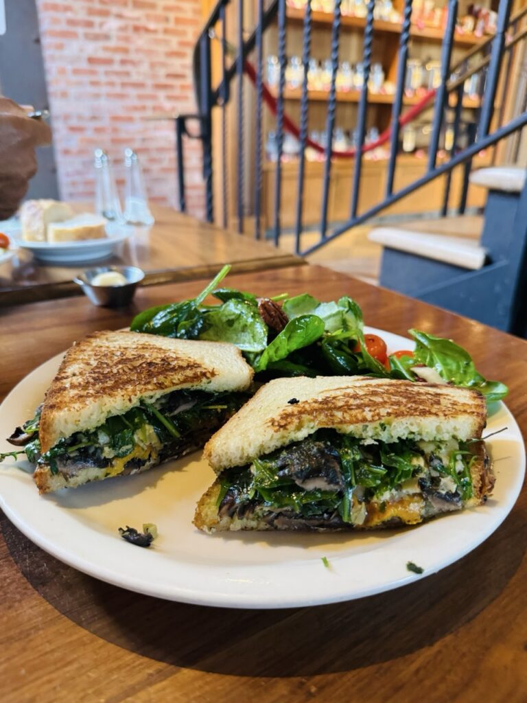 Plate with a a roasted vegetable and portobello mushroom panini with side salad.