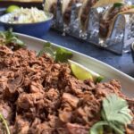 Platter of jackfruit carnitas with tacos in the background.