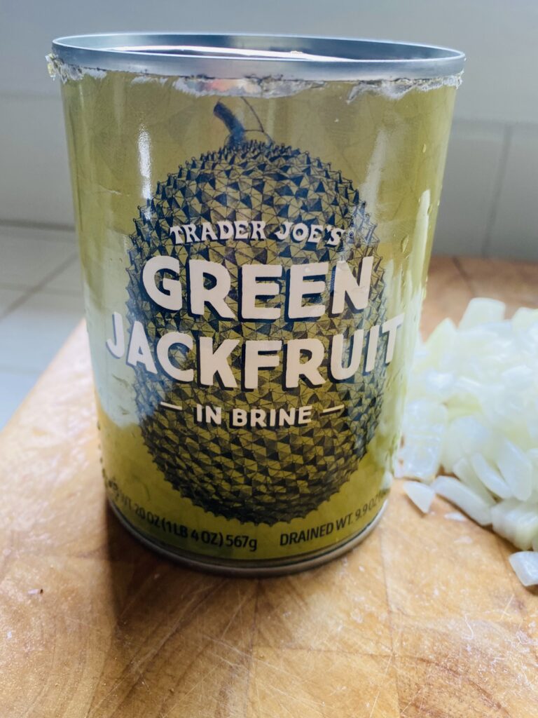 A can of green jackfruit sitting on a cutting board.