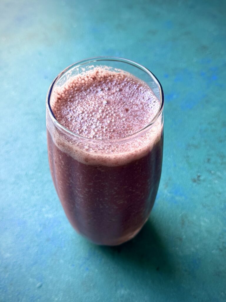 Glass filled with cherry smoothie with a green background