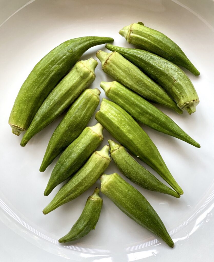 Fresh whole okra arranged on a plate.