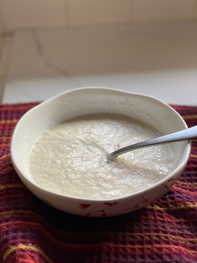 Bowl filled with vegan buttermilk with a spoon in it.