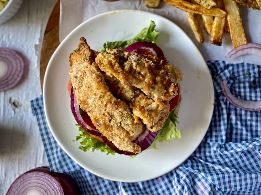 Open-faced oyster mushroom sandwich with lettuce and tomatoes, a side of oven fries.