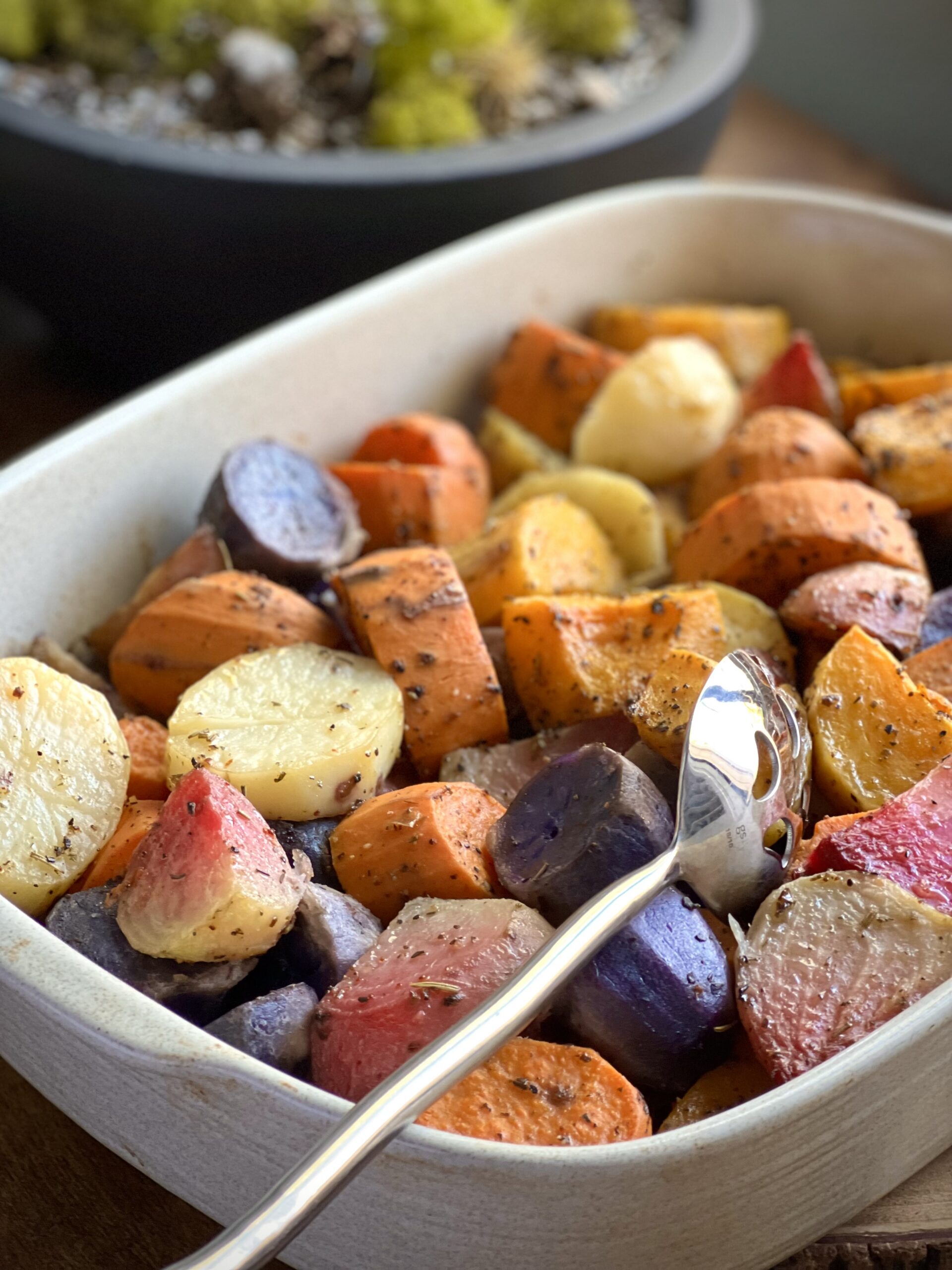 Casserole dish filled with pieces of roasted root vegetables of various colors.